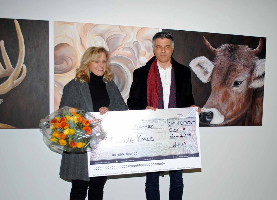 Die Kunstschaffende Nicole Nicole Krebs aus Ennenda konnte, hier vor ihren drei Werken, von HansueliLeisinger den von der GlarnerSach gespendeten Publikumspreis entgegennehmen. (Bild: a.lombardi)