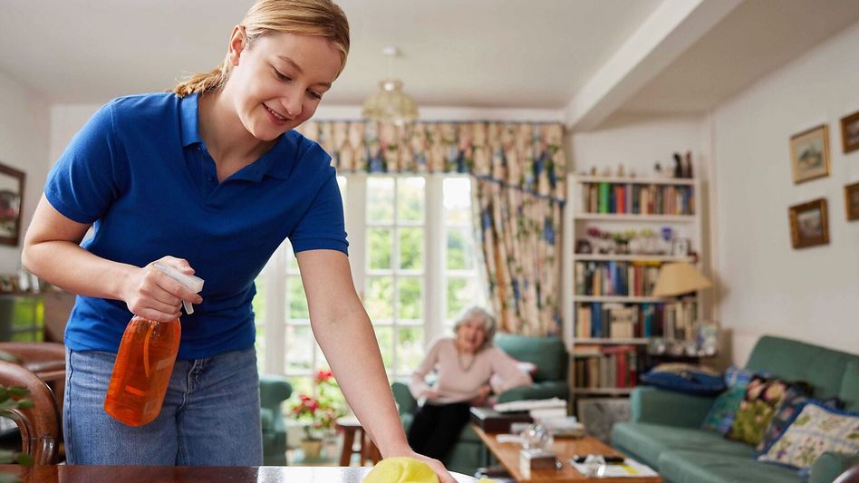 Eine Betreuungsperson hilft einer Seniorin beim Reinigen der Wohnung • (Foto: iStock)