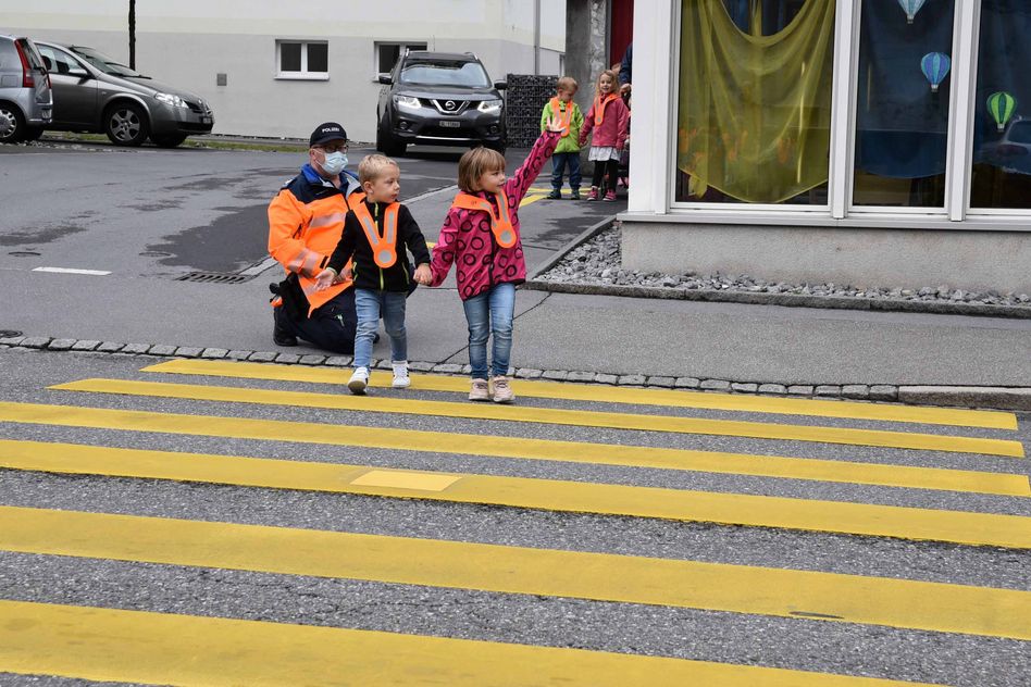 Polizist Christian Eggenberger übt mit den Kindergartenkinder von Netstal das richtige Überqueren der Hauptstrasse. (Bilder: jhuber)
