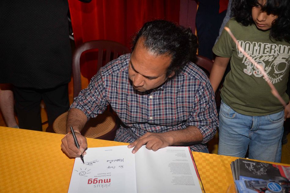 Der Fotograf Sasi Subramaniam signiert das Buch unter den Kontrollblicken seines Sohnes